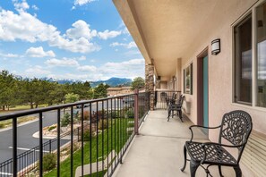 A balcony with a view of a road and mountains, a stone pillar, and a chair. - Best Western Plus Silver Saddle Inn (Estes Park)