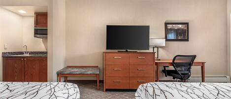 A hotel room with two beds, a desk with a chair, a television, a small cabinet, and a picture on the wall.