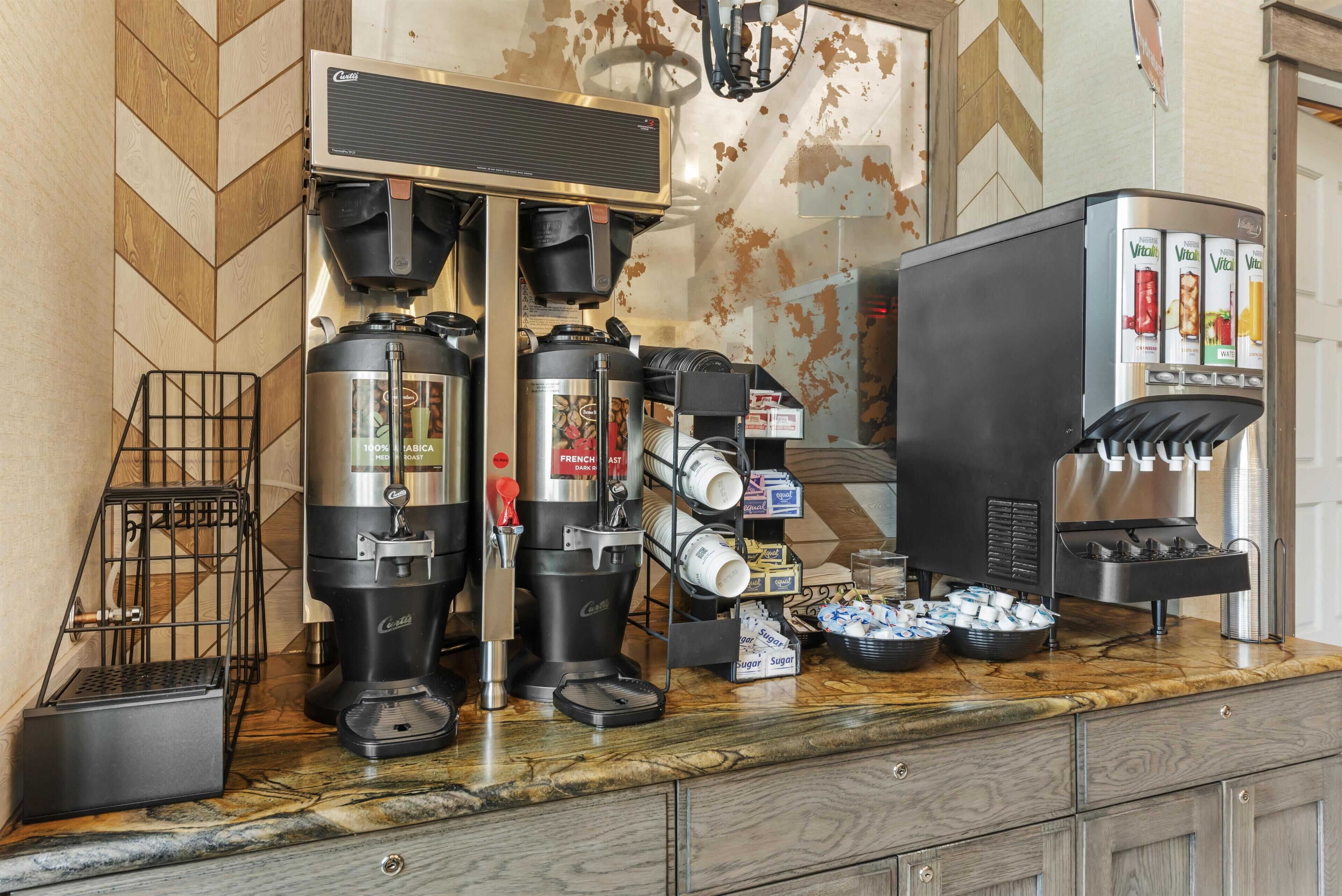 Un espace dédié au café, équipé de plusieurs machines à café, d’un distributeur de sucre et d’un distributeur de boissons.