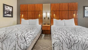 A hotel room with two beds, a wooden headboard, a mirror, bedside lamps, and a framed picture on the wall. - Best Western Plus Silver Saddle Inn (Estes Park)