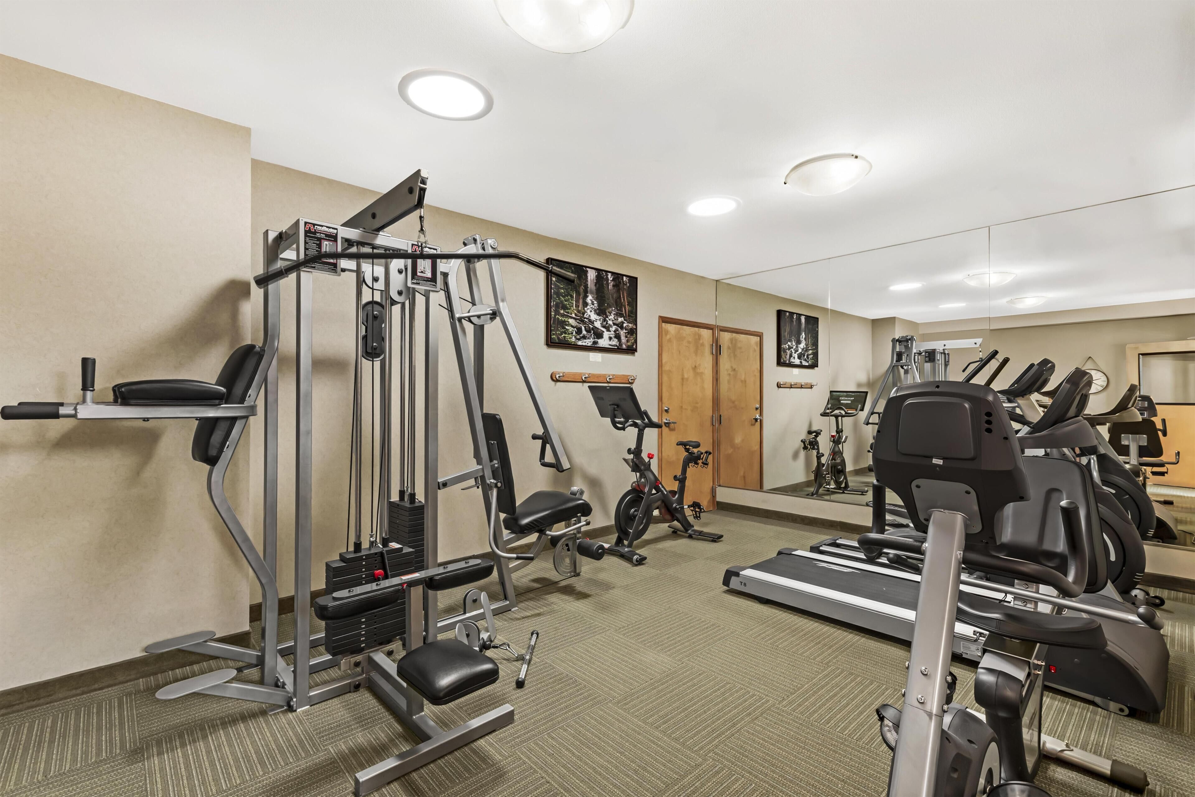 A gym with cardio machines, weightlifting equipment, and a mirrored wall.