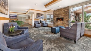 A modern lounge area with sofas, armchairs, a fireplace, and large windows offering views. - Best Western Plus Silver Saddle Inn (Estes Park)