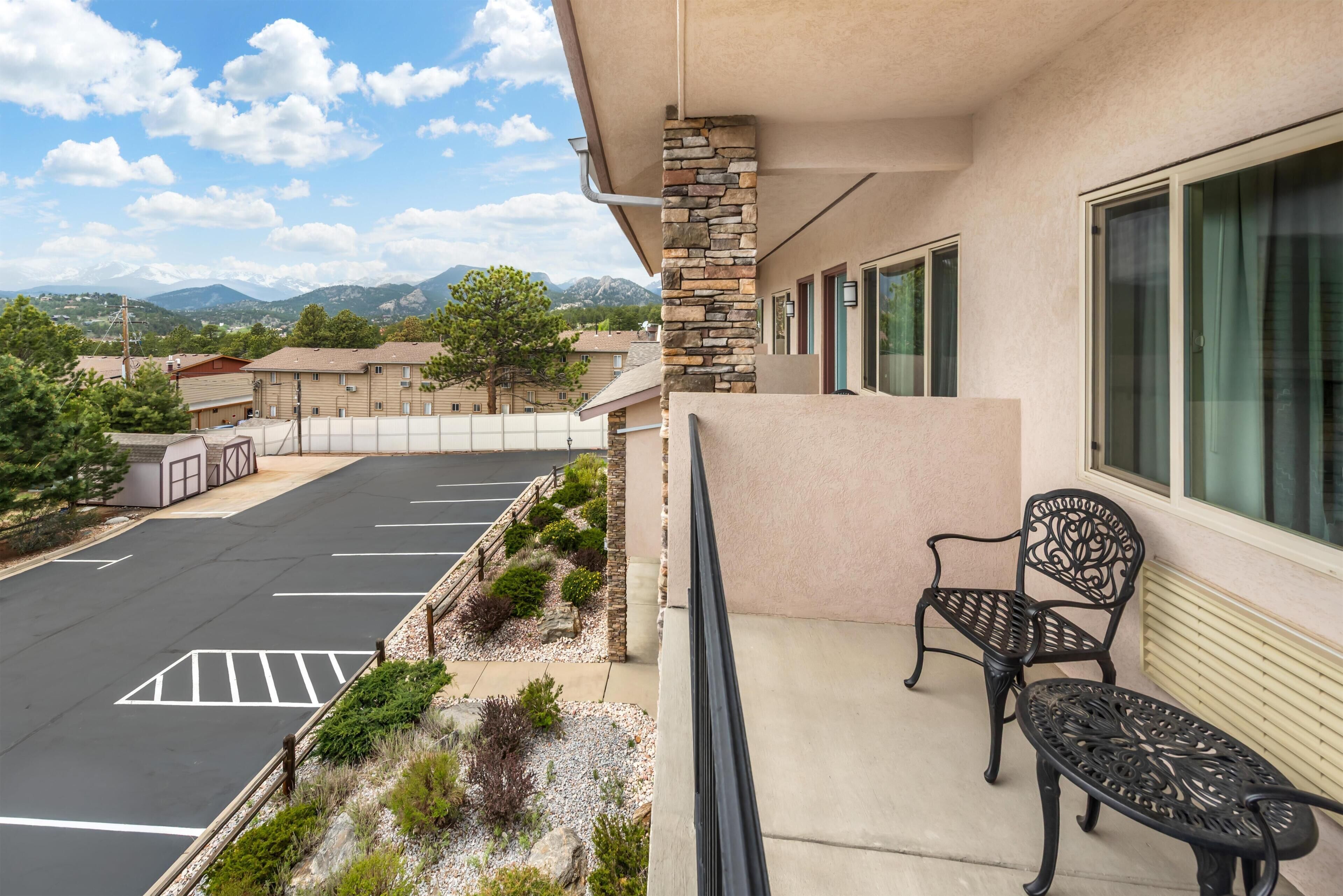 A hotel with a parking lot, a balcony with a chair, and a mountain view.