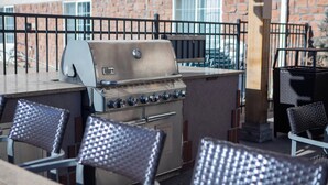 Ein Grillbereich im Freien mit Backsteinwand und Metallzaun.