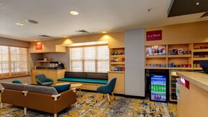 Eine Hotelhalle mit Sitzgelegenheiten, einem Getränkeautomaten und einer Snackbar.