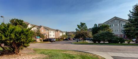 A residential area with apartment buildings, a parking lot, and a well-maintained lawn.