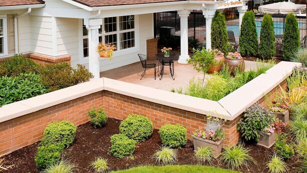 A white building with a covered patio area, a brick pathway, and a small pool. - Sonesta Simply Suites Seattle Renton (Renton)