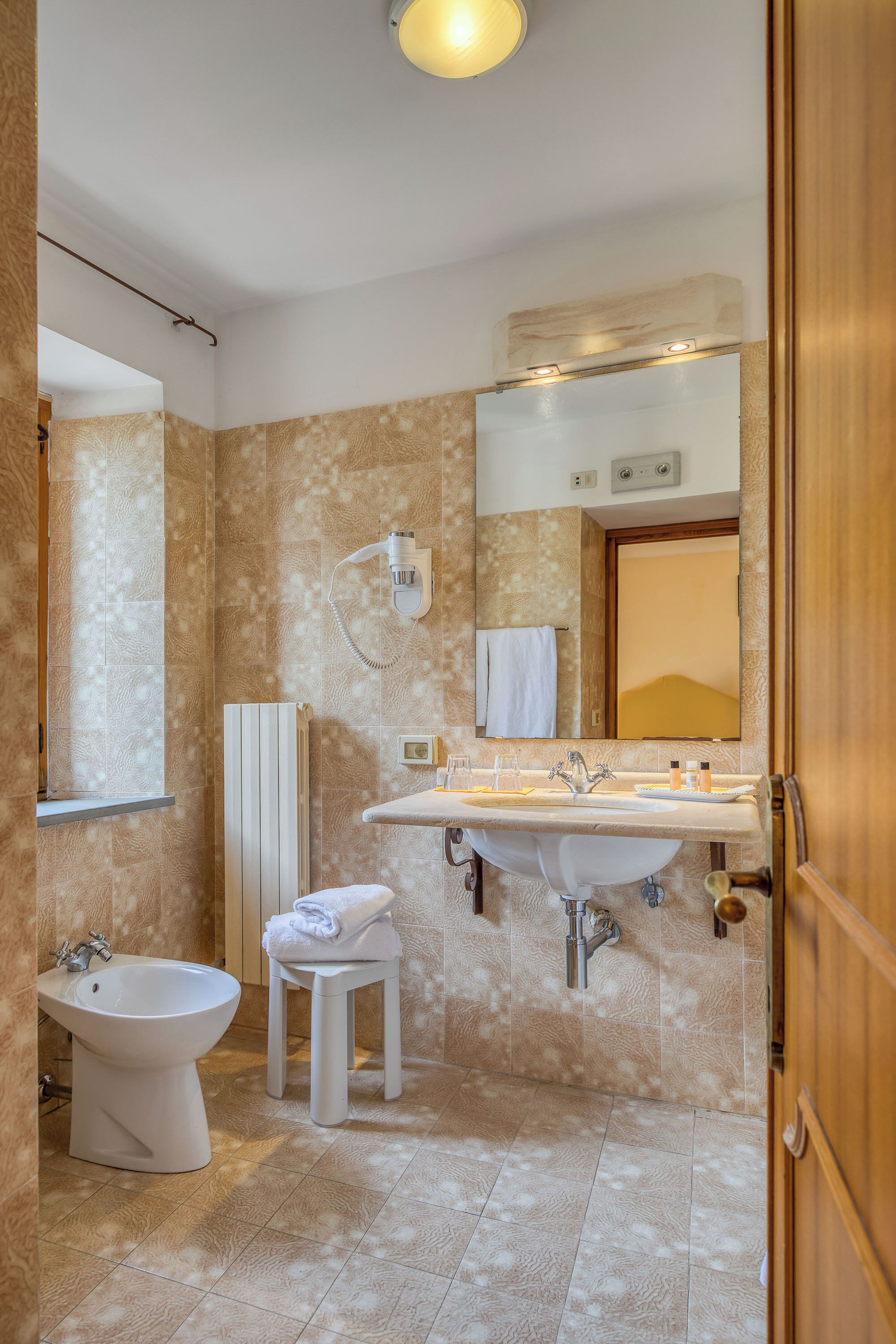 A bathroom with a bidet, sink, and mirror.