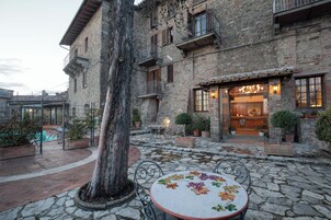 Un edificio de piedra con patio, mesas al aire libre y piscina.