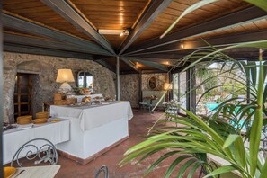 A covered outdoor dining area with stone walls, a pool, and potted plants. - Relais La Fattoria (Passignano sul Trasimeno)