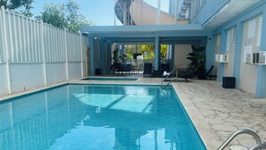 A swimming pool with clear blue water, surrounded by a tiled deck and a covered seating area. - Parador Boquemar (Cabo Rojo)