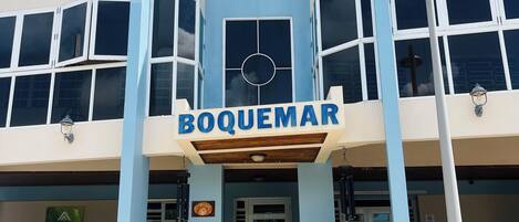 A building with a sign reading "BOQUEMAR" and a logo above the entrance.