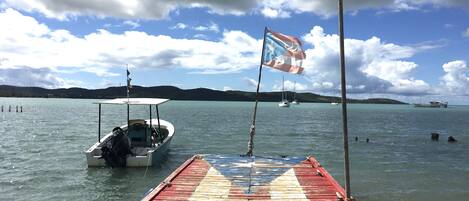A wooden pier with a flag, boats, and a distant island.