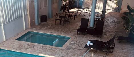 An indoor swimming pool with a stone floor, a diving board, and lounge chairs.