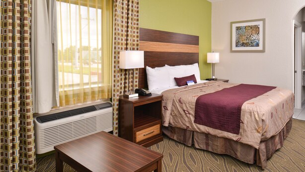 A hotel room with a bed, bedside tables, a desk, and a window with curtains.