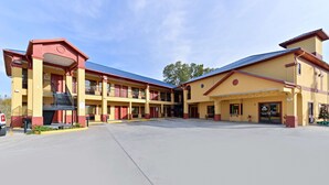 A multi-story motel with a central courtyard, balconies, and a covered parking area.