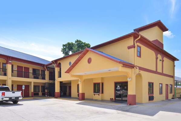 A two-story building with a yellow facade and red trim, featuring a covered entrance and a visible staircase. - Americas Best Value Inn & Suites Houston Downtown (Houston)