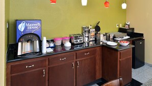 A hotel kitchen counter with a coffee machine, toasters, and a waffle maker.