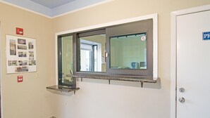A hallway with a door labeled "PR" and a window with a shelf above it.