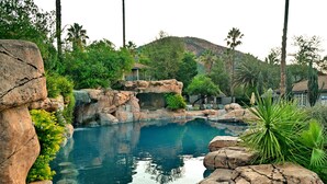 Una piscina rodeada de rocas y vegetación, con una montaña al fondo.