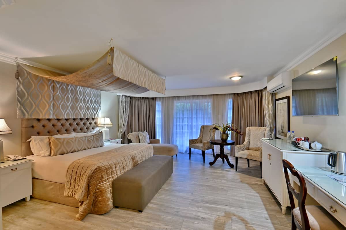 Une chambre d’hôtel avec un grand lit, un bureau, une chaise, un canapé et une télévision.