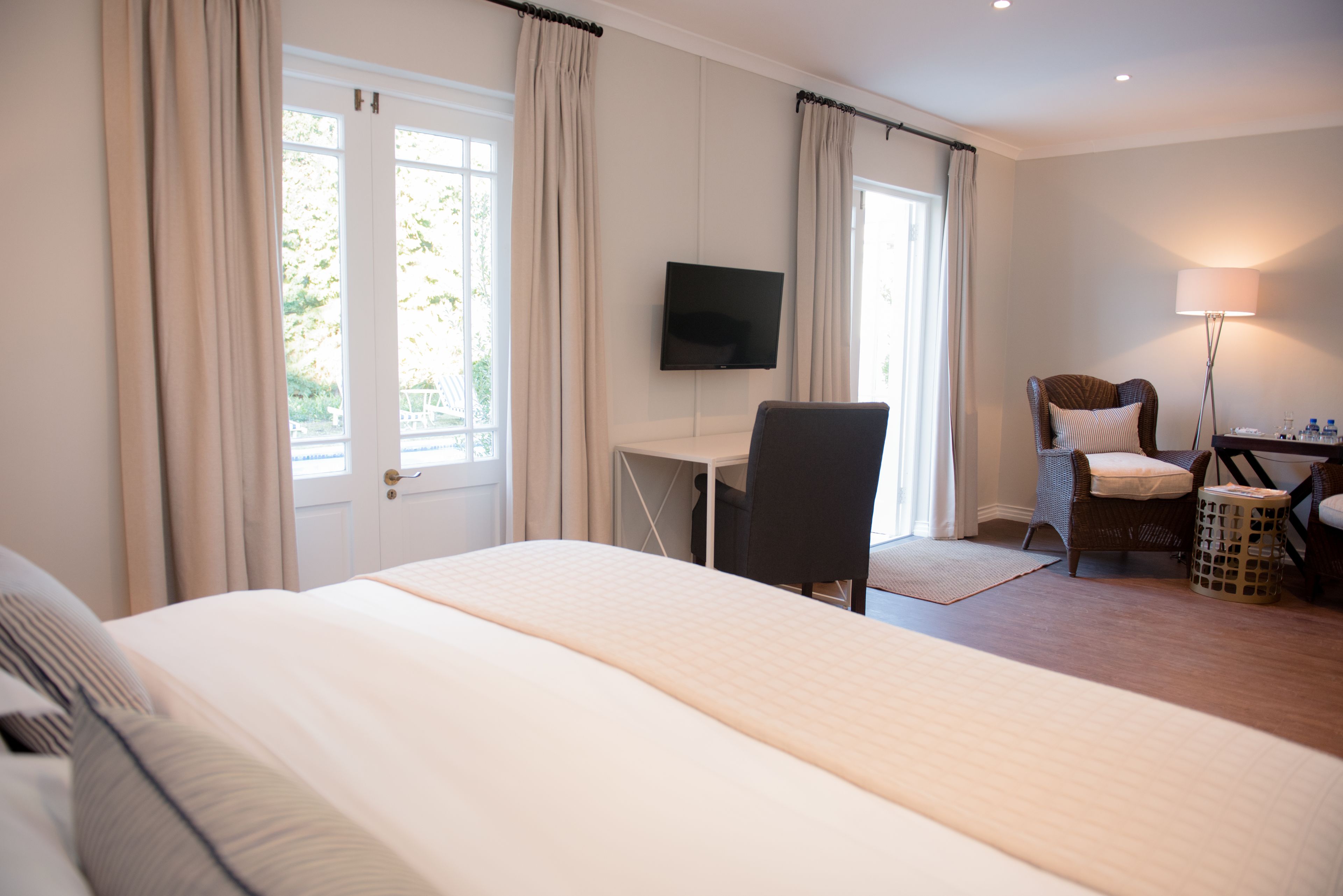 Una habitación de hotel con una cama grande, un escritorio con una silla, un televisor y una lámpara.