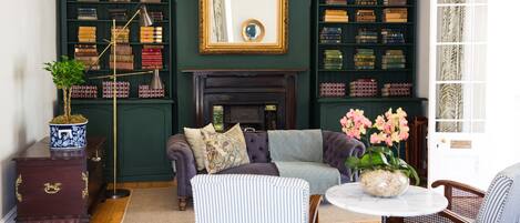 A cozy living room with a fireplace, bookshelves, and comfortable seating.