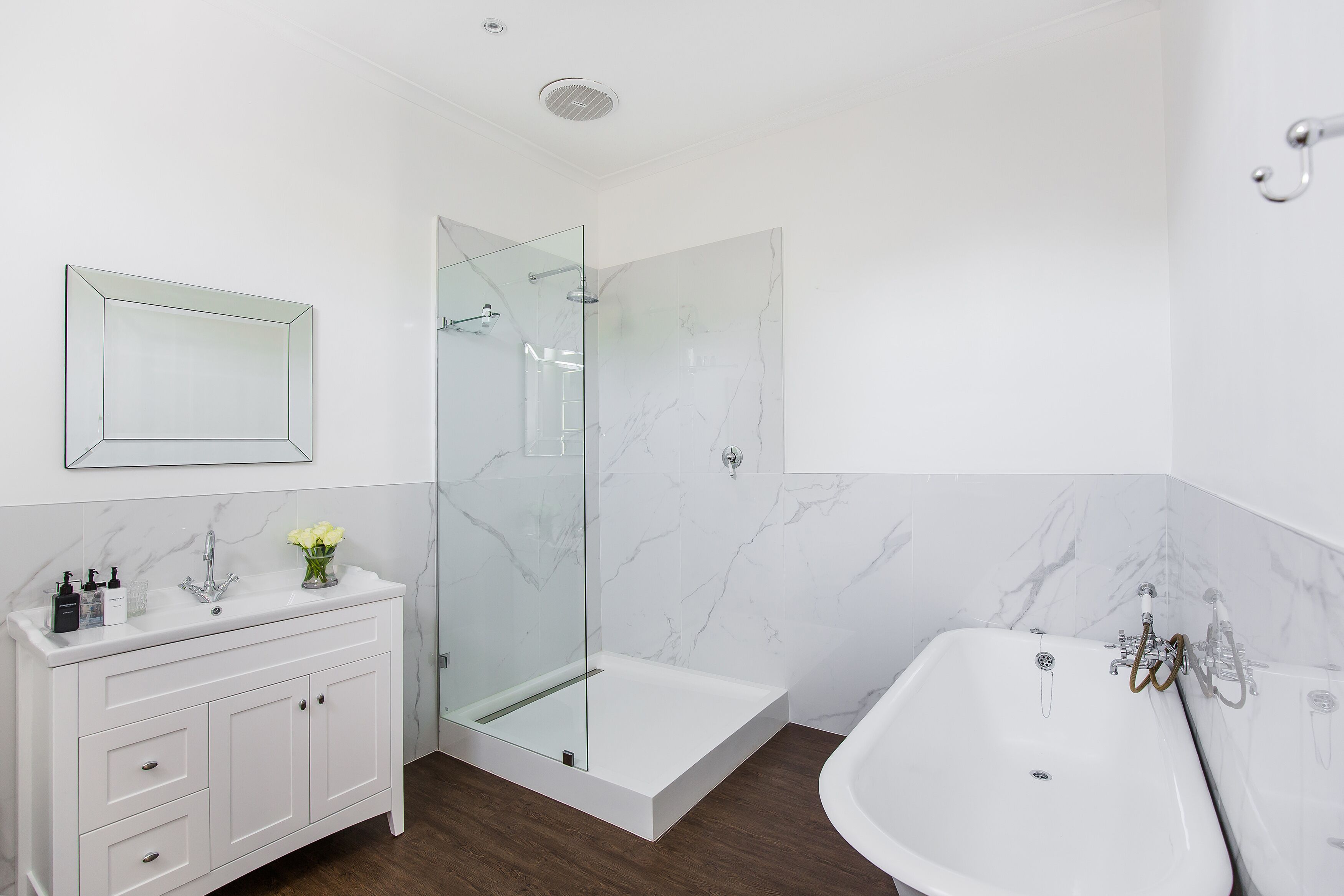 A modern bathroom with a glass-enclosed shower, a white vanity with drawers, and a freestanding bathtub.