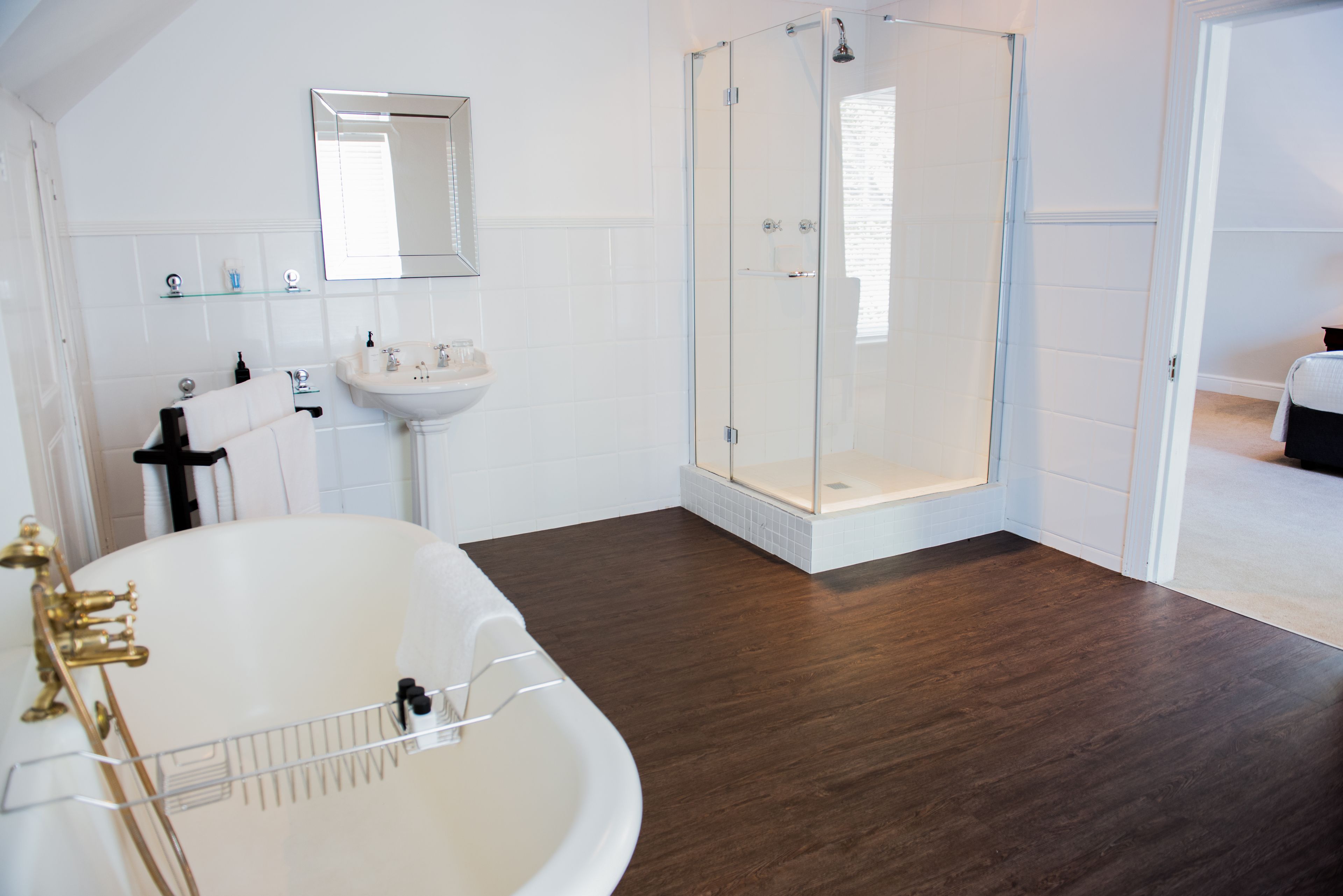 A bathroom with a bathtub, a glass-enclosed shower, a sink, and a mirror.