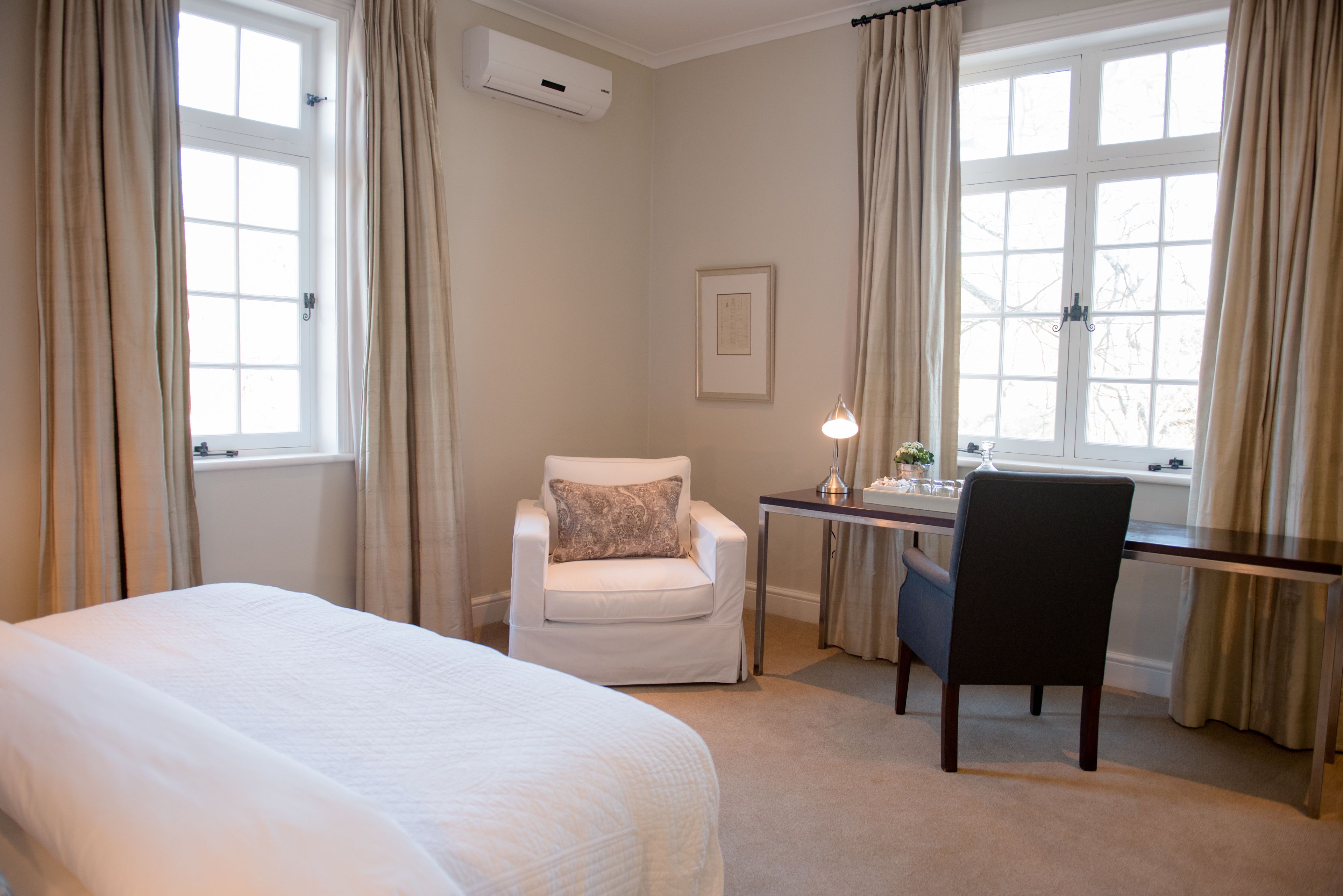 A hotel room with a bed, a desk, a chair, and a window with curtains.