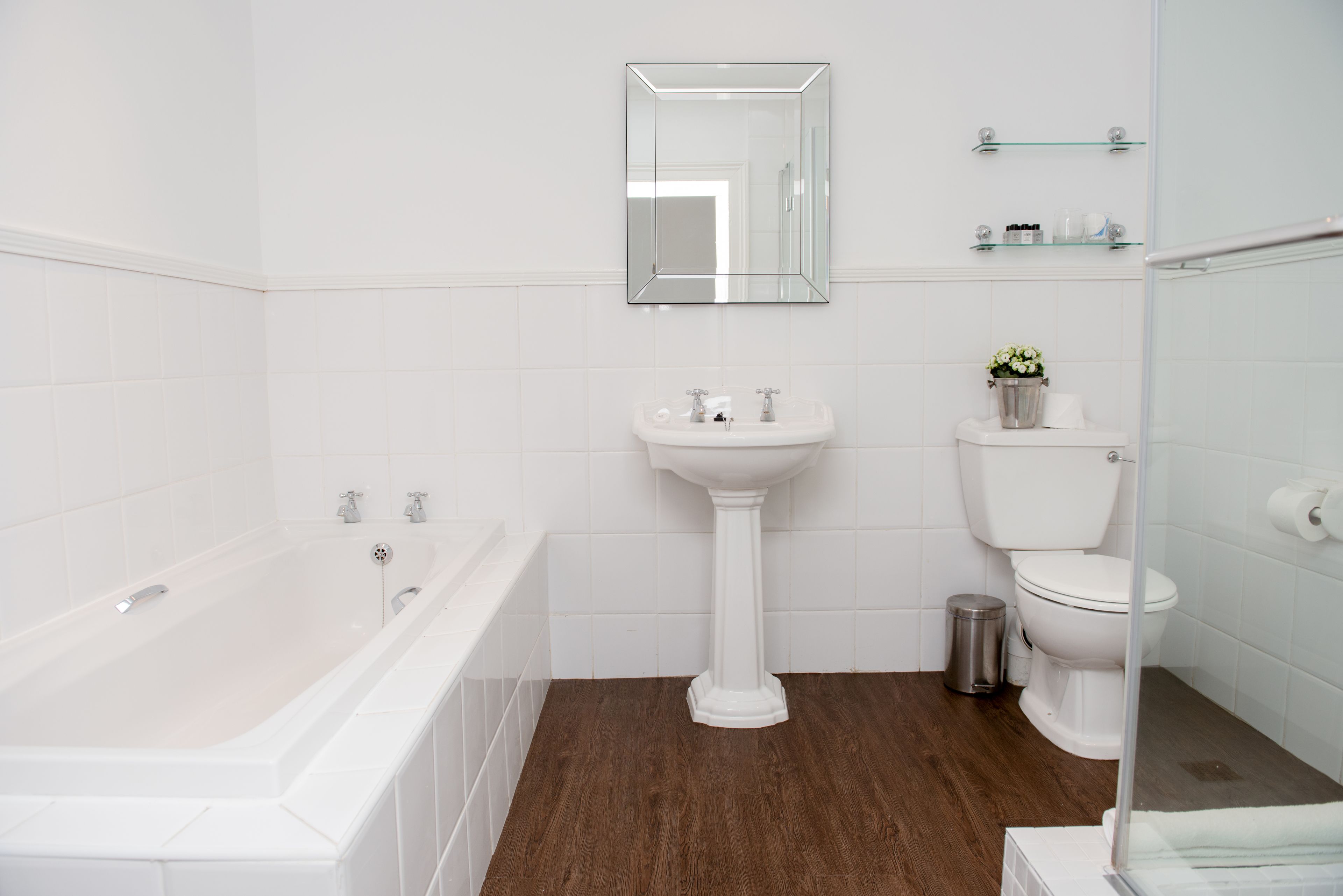 A bathroom with a bathtub, pedestal sink, and toilet.