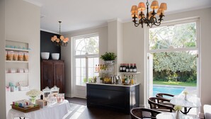 Une pièce spacieuse avec vue sur la piscine, un coin bar avec des bouteilles et un espace repas avec des chaises et des tables.