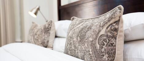A neatly made bed with patterned pillows and a bedside lamp.