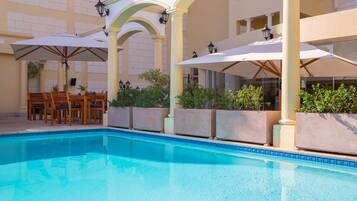 Alberca al aire libre, sombrillas en la alberca y camastros