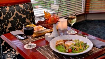 A dining table with a plate of salad, a glass of wine, and a vase with a decorative plant.