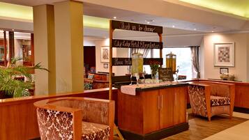 Un hall d’hôtel avec des meubles en bois, un comptoir de réception et une enseigne sur laquelle on peut lire : « Merci d’avoir choisi l’hôtel City Lodge Bloemkantoor. »