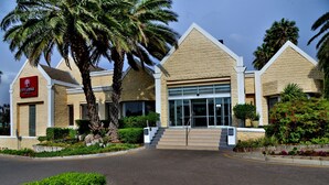 A hotel with a modern design, featuring a prominent entrance with a glass facade and a staircase leading up to the door.