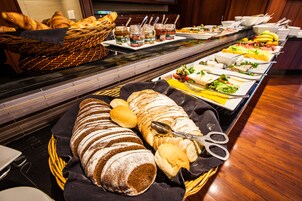 A buffet with various breads, pastries, and condiments.