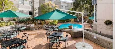 Una piscina al aire libre, sombrillas, sillones reclinables de piscina