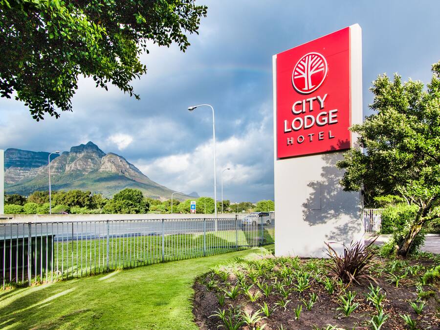 En skylt för hotellet City Lodge, med ett berg i bakgrunden.