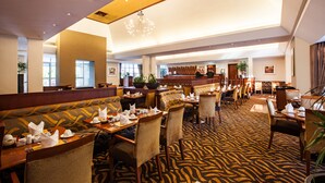 Un restaurante espacioso con techos altos, iluminación moderna y alfombra estampada.