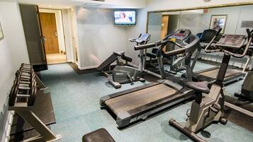 Un gimnasio con cintas de correr, máquinas de pesas y una pantalla de televisión.