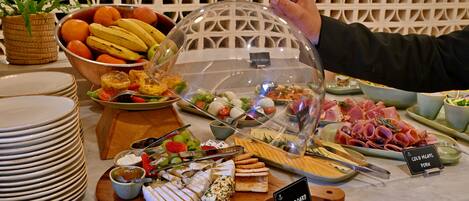 A buffet with various food items including fruits, cheeses, and meats.