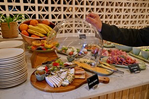 A buffet with various food items including fruits, cheeses, and meats.