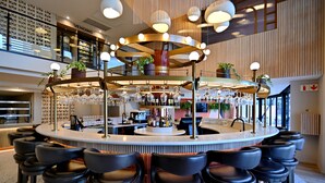 Un espace bar moderne doté d’un bar circulaire, de nombreux tabourets et d’une grande variété de bouteilles et de verres.