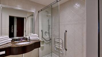 A modern bathroom with a glass-enclosed shower, a marble sink, and a white tiled floor.