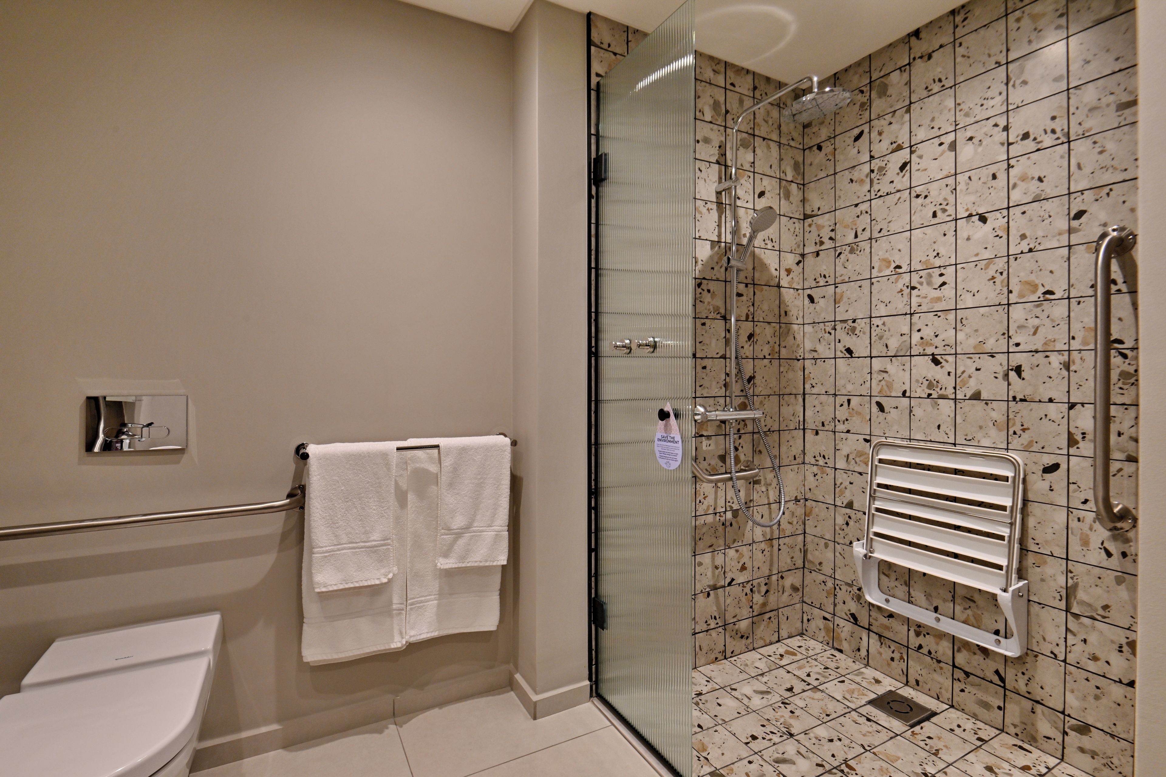 Een badkamer met een douche met glazen wand, een toilet en een handdoekrek.