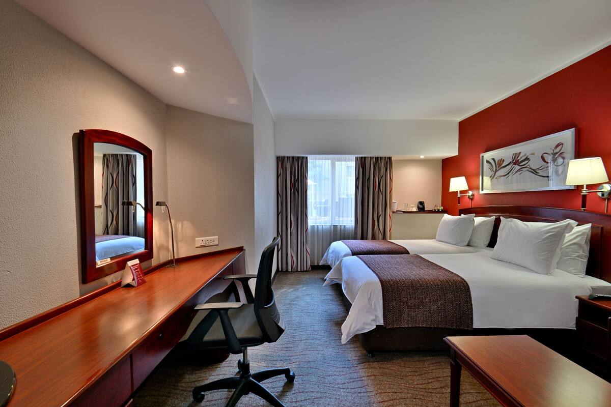 Une chambre d’hôtel avec un lit, un bureau, une chaise et un grand miroir.