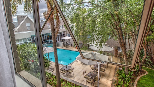 A view of a swimming pool with outdoor seating and surrounding greenery.