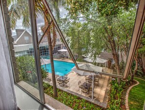 A view of a swimming pool with outdoor seating and surrounding greenery. - City Lodge Hotel Bryanston (Sandton)